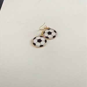 May include: A pair of gold earrings with a black and white soccer ball design.