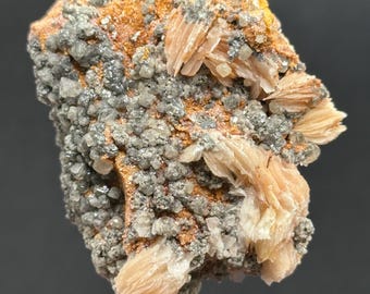May include: A cluster of pale pink barite crystals with a silvery gray mineral matrix. The barite crystals are arranged in a fan-like pattern.