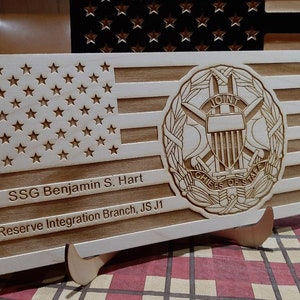May include: A wooden plaque with an American flag design, the Joint Chiefs of Staff seal, and the text "SSG Benjamin S. Hart Reserve Integration Branch, JS J1".