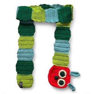 May include: A handmade crochet scarf in the shape of a caterpillar. The scarf features alternating sections of green, blue, and yellow-green. The caterpillar's head is red with green and white eyes and blue antennae. A unique, whimsical accessory.