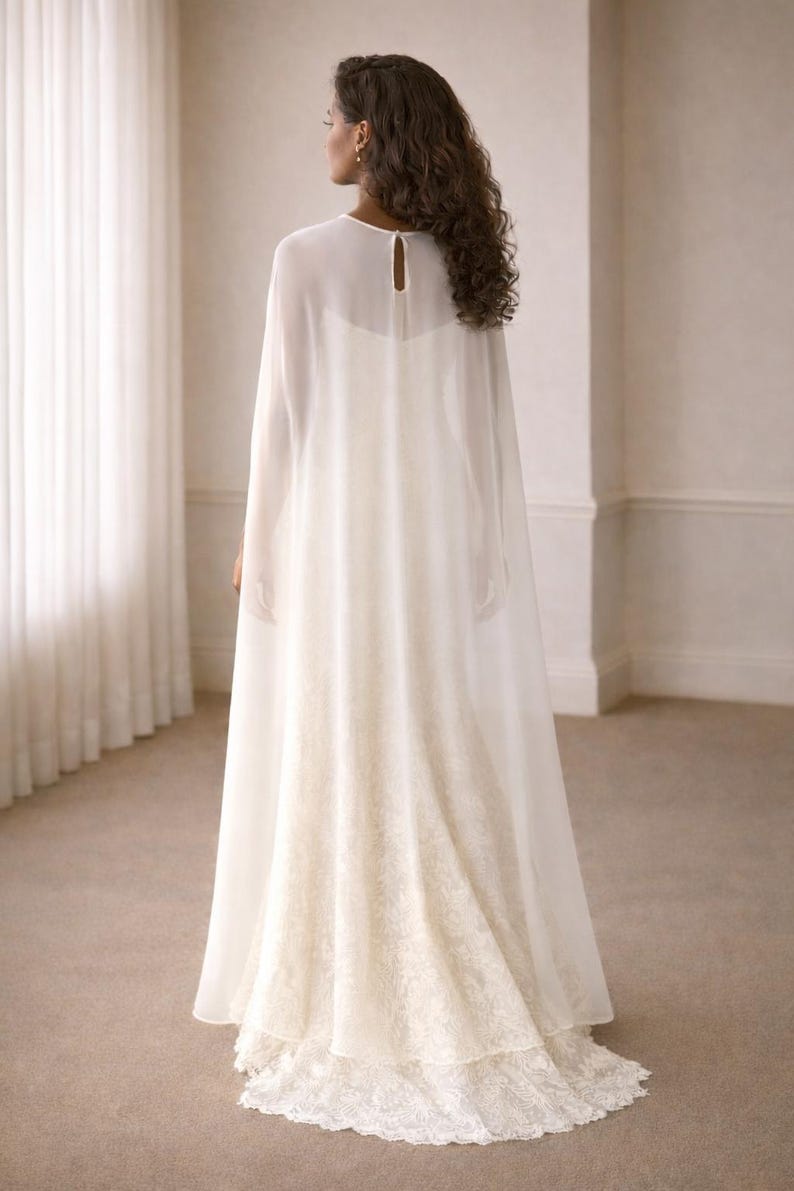 Beautiful bride in a modern white chiffon evening cape dress with a flowing sheer overlay and elegant satin base, standing gracefully against a soft beige background with warm studio lights highlighting her natural beauty. The chiffon cape adds ethereal movement, perfect for bridal photoshoots, rehearsal dinners, or wedding receptions. A minimalist yet luxurious fashion choice for the modern bride seeking timeless elegance.
