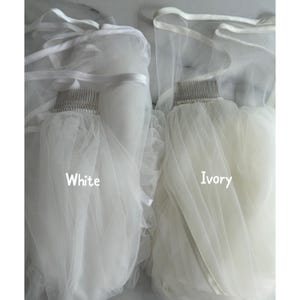 May include: Two bridal veils, one white and one ivory, are displayed. Each veil is attached to a comb and features a soft, flowing fabric. The text "White" and "Ivory" are printed on the veils.