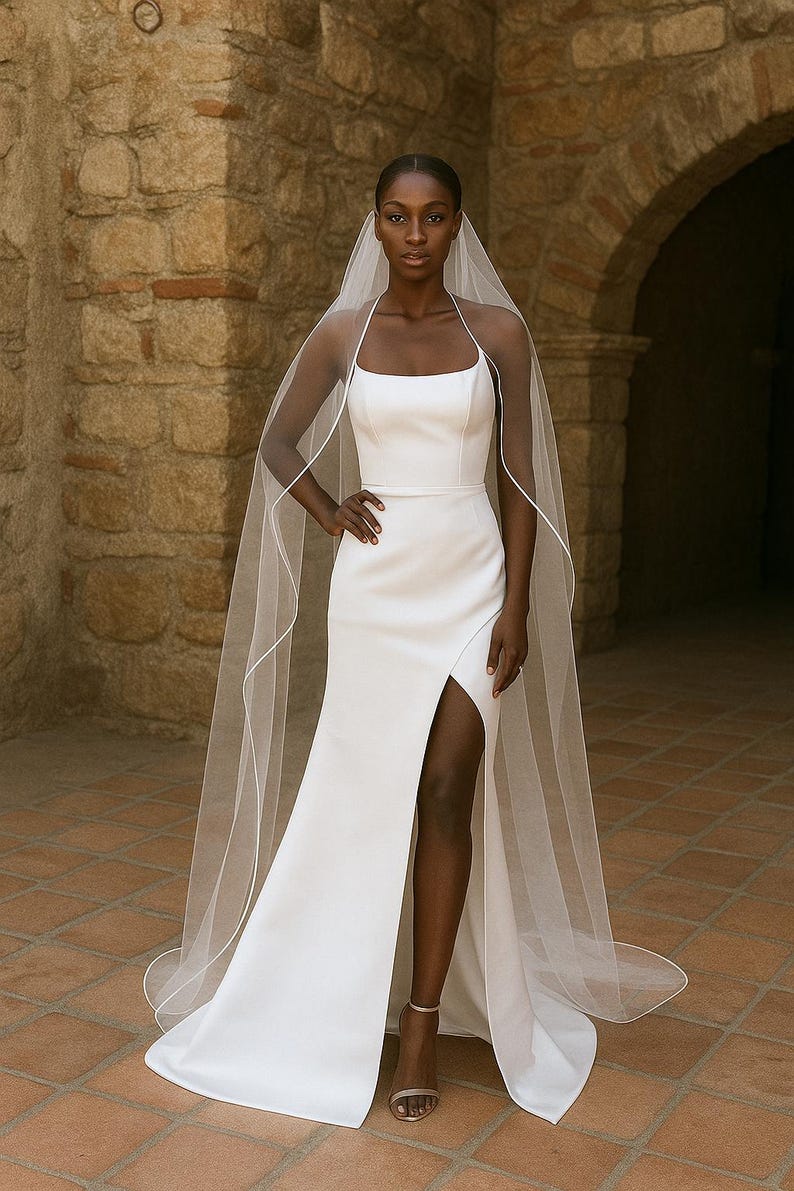 Full Standing Front image of a dark-skinned bridal model while wearing a Ivory tulle satin edge veil. The soft beige background highlights her radiant expression and the elegant detailing of the veil.