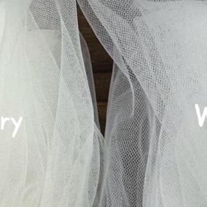 Side-by-side close-up of bridal soft tulle swatches labeled "Ivory" and "White" showing color and texture differences; ivory appears warm and creamy while white is brighter and crisp. Perfect for brides choosing between white and ivory wedding veils with blusher; highlights sheer, lightweight tulle weave and tonal match against gowns. Suitable for Etsy listings, fabric comparison, and veil color selection.
