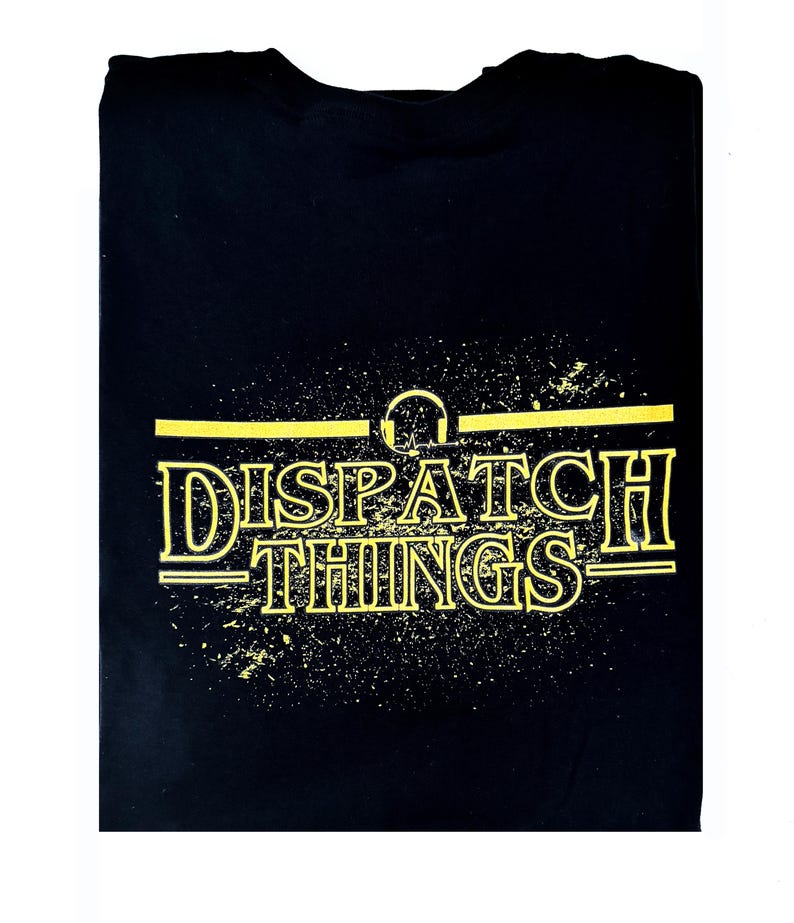 May include: Black t-shirt with a yellow graphic print of the text "DISPATCH THINGS" with a headphone symbol above the text.
