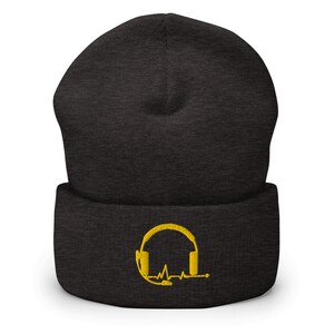May include: A black beanie with a yellow embroidered design of headphones with a heartbeat line.