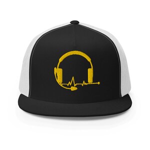 May include: Black and white trucker cap with a black peak and a white mesh back. The front panel has a gold embroidered design of headphones and a heartbeat line. A stylish accessory for music lovers and audio professionals.