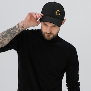 May include: A black distressed baseball cap with a yellow embroidered design of headphones. The cap has a curved brim and a structured crown.