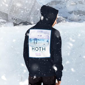 Könnte beinhalten: Ein marineblauer Hoodie mit einem Aufdruck auf der Rückseite. Der Aufdruck ist ein Aquarell-artiges Bild eines Star Wars AT-AT Walkers in einer schneebedeckten Landschaft. Der Text "HOTH - ECHO BASE - Outer Rim Territories" ist unter dem Bild gedruckt.