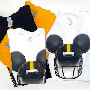 May include: Four t-shirts, one white with a black and yellow football helmet with Mickey Mouse ears, one black, and two yellow.