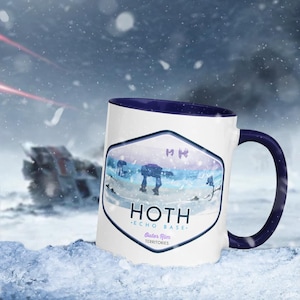 May include: A white ceramic mug with a blue rim and handle. The mug features a graphic of an AT-AT walker in a snowy landscape with the text "HOTH - ECHO BASE - Outer Rim Territories".