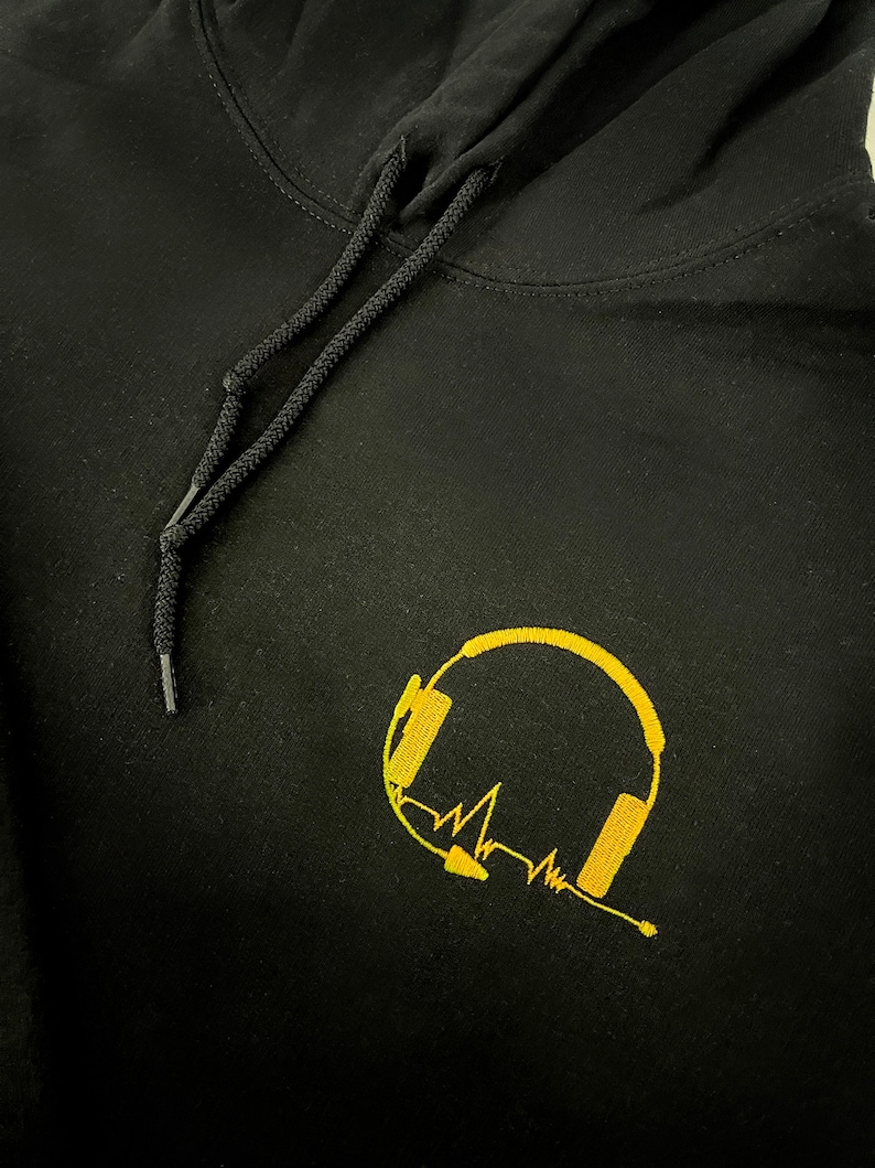 May include: Black hoodie with a gold embroidered design of headphones and a heartbeat line.