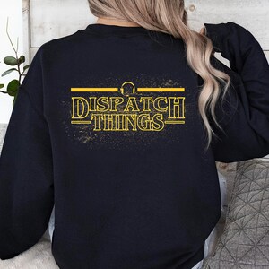 May include: Black sweatshirt with a yellow graphic that says "DISPATCH THINGS" with a headphone symbol above the text.