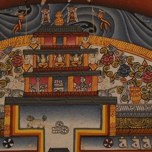 May include: A colorful Tibetan Buddhist painting depicting a mandala with a central stupa, surrounded by intricate floral designs and figures. The painting features a blue, white, and gold color scheme.