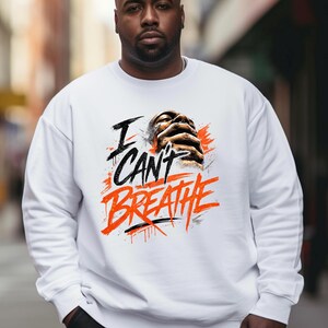 Puede incluir: Una sudadera blanca de cuello redondo con un estampado gráfico en el pecho. El diseño incluye el texto "I CAN'T BREATHE" en letras negras y naranjas llamativas, junto a una ilustración de unas manos entrelazadas.