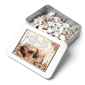 Può includere: Una scatola rettangolare in metallo argentato contenente un puzzle. Il coperchio presenta un'immagine stampata di una persona che legge un libro tra i fiori, con testo in spagnolo tra cui Proverbios 31:10 e Mujer con Propósito, bordato di marrone.