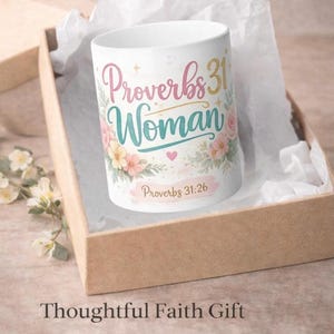 May include: A white ceramic mug with the words "Proverbs 31 Woman" in pink and teal script, adorned with floral accents. The mug is presented in a gift box with the text "Thoughtful Faith Gift" at the bottom.