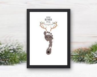 May include: A framed print with a brown footprint in the shape of a reindeer with a smiling face. The reindeer has antlers with colorful lights and the text "Cutest Reindeer of All" above the footprint.