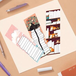 May include: Three colorful bookmarks featuring a stack of books, a tree with pink flowers, and a bookshelf with cats. Each bookmark has a blank space for writing.