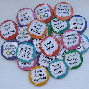 May include: A collection of colorful round buttons with various phrases related to neurodiversity and disabilities. The buttons feature text like "I am autistic," "I am deaf," and "Please don't touch me." The buttons are in various colors.