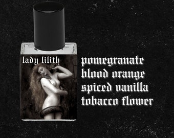 May include: A small glass bottle of perfume with a black cap. The label says "lady lilith" and lists the fragrance notes: pomegranate, blood orange, spiced vanilla, and tobacco flower.