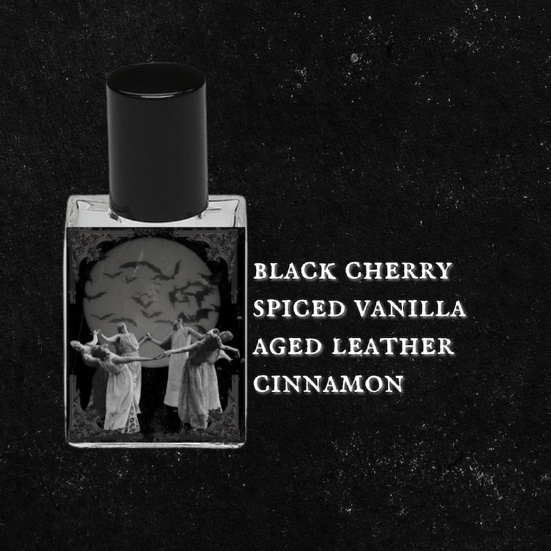 May include: A black glass bottle with a black cap and a label that reads "BLACK CHERRY SPICED VANILLA AGED LEATHER CINNAMON". The label features a black and white illustration of a group of people dancing in front of a full moon with bats flying around it.
