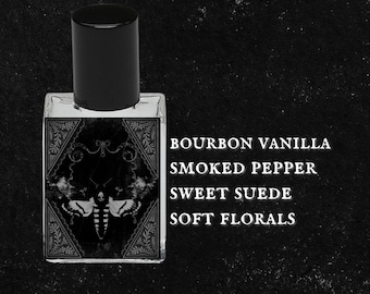 May include: A black glass bottle with a black cap, featuring a label with the text "BOURBON VANILLA SMOKED PEPPER SWEET SUEDE SOFT FLORALS". The bottle has a decorative design with a moth on the front.