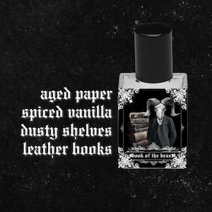 Puede incluir: Una peque&ntilde;a botella de vidrio de perfume con una tapa negra. La etiqueta presenta una ilustraci&oacute;n en blanco y negro de una criatura parecida a una cabra que lleva un traje y sostiene una pila de libros. El texto en la etiqueta dice "Book of the Beast". El texto "papel envejecido, vainilla especiada, estantes polvorientos, libros de cuero" est&aacute; escrito en blanco sobre un fondo negro.