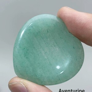 May include: A heart-shaped green aventurine crystal. The crystal is smooth and polished, with a light green color and a subtle sparkle.
