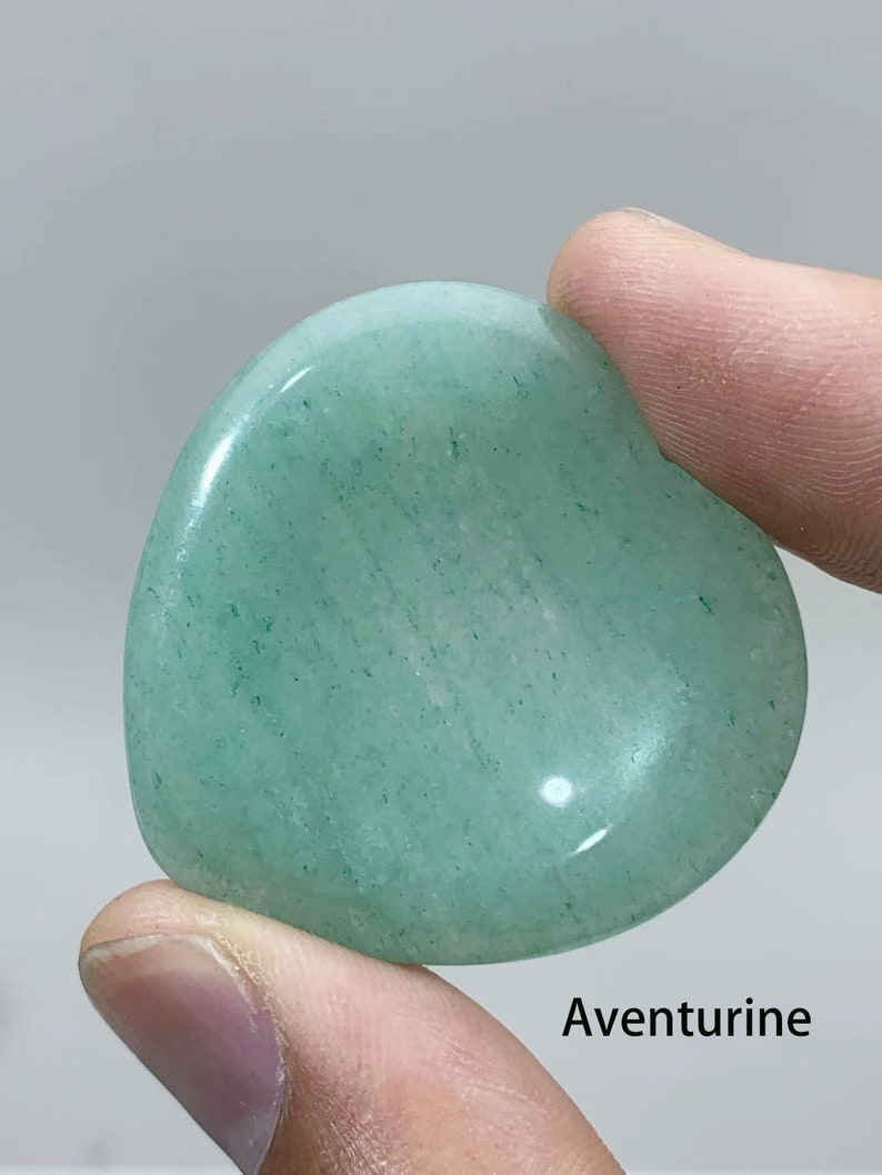 May include: A heart-shaped green aventurine crystal. The crystal is smooth and polished, with a light green color and a subtle sparkle.
