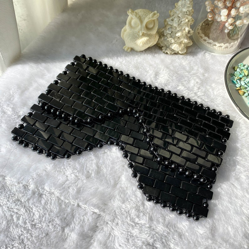 Pu&ograve; includere: Maschera per gli occhi nera realizzata con piccole piastrelle quadrate nere con perline nere attorno ai bordi. La maschera &egrave; progettata per essere indossata sugli occhi.