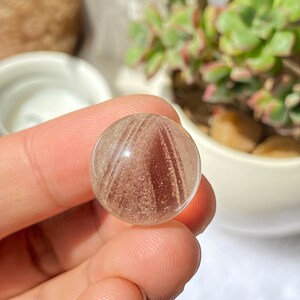 K&ouml;nnte beinhalten: Eine klare, durchsichtige Kugel mit braunen und wei&szlig;en Streifen. Die Kugel hat einen Durchmesser von etwa 1,8 cm. C-(0.7",8g)