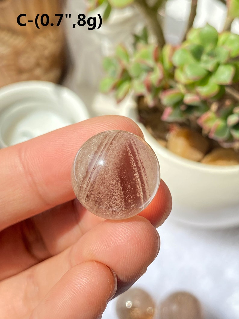 K&ouml;nnte beinhalten: Eine klare, durchsichtige Kugel mit braunen und wei&szlig;en Streifen. Die Kugel hat einen Durchmesser von etwa 1,8 cm. C-(0.7",8g)