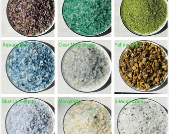 May include: Nine small bowls filled with various types of tumbled gemstones, including green aventurine, clear moonstone, blue lace agate, and yellow tiger's eye.
