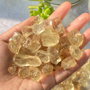 Puede incluir: Una colección de piedras preciosas talladas en bruto de color amarillo dorado translúcido. Las piedras son de varios tamaños y formas, y tienen un aspecto natural sin pulir.