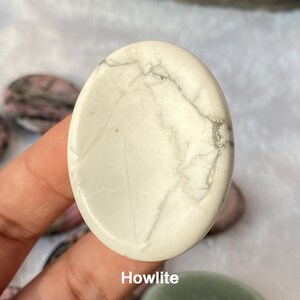 Może przedstawiać: Biały kamień palmowy z howlitu o gładkiej, wypolerowanej powierzchni i naturalnym, żyłkowatym wzorze.