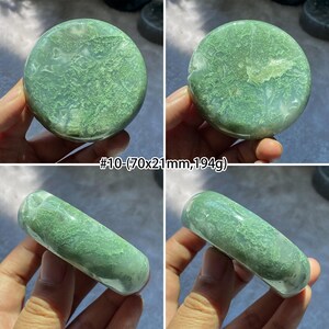 Peut inclure: Quatre images pr&eacute;sentent une pierre d'agate mousse verte. Deux images montrent une pierre ronde et plate, et deux montrent une pierre cylindrique. Le texte "#10 - (70x21mm, 194g)" est visible. La pierre a un motif naturel unique.