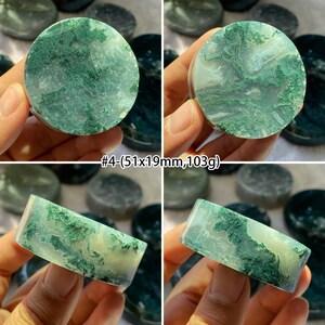 Peut inclure: Plusieurs pierres d'agate mousse vertes et blanches. Les pierres sont rondes et rectangulaires, avec un aspect marbr&eacute; naturel. Le texte "#4-(5.1x1.9cm,103g)" est visible. Les pierres sont tenues dans une main.