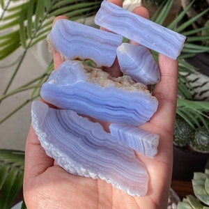 May include: A collection of blue agate stones with white banding. The stones are smooth and polished, and they have a variety of shapes and sizes.