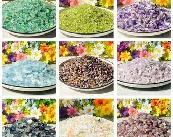 May include: Assortment of colorful crushed glass stones in various colors, including green, purple, pink, blue, and white. The stones are displayed in small bowls with a floral background.