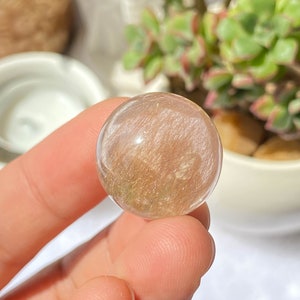 K&ouml;nnte beinhalten: Eine klare, durchscheinende Kugel mit goldenen Flocken und einem leichten Rosaton. Die Kugel hat einen Durchmesser von etwa 2 cm und wiegt 12 Gramm. B-(0.8",12g)