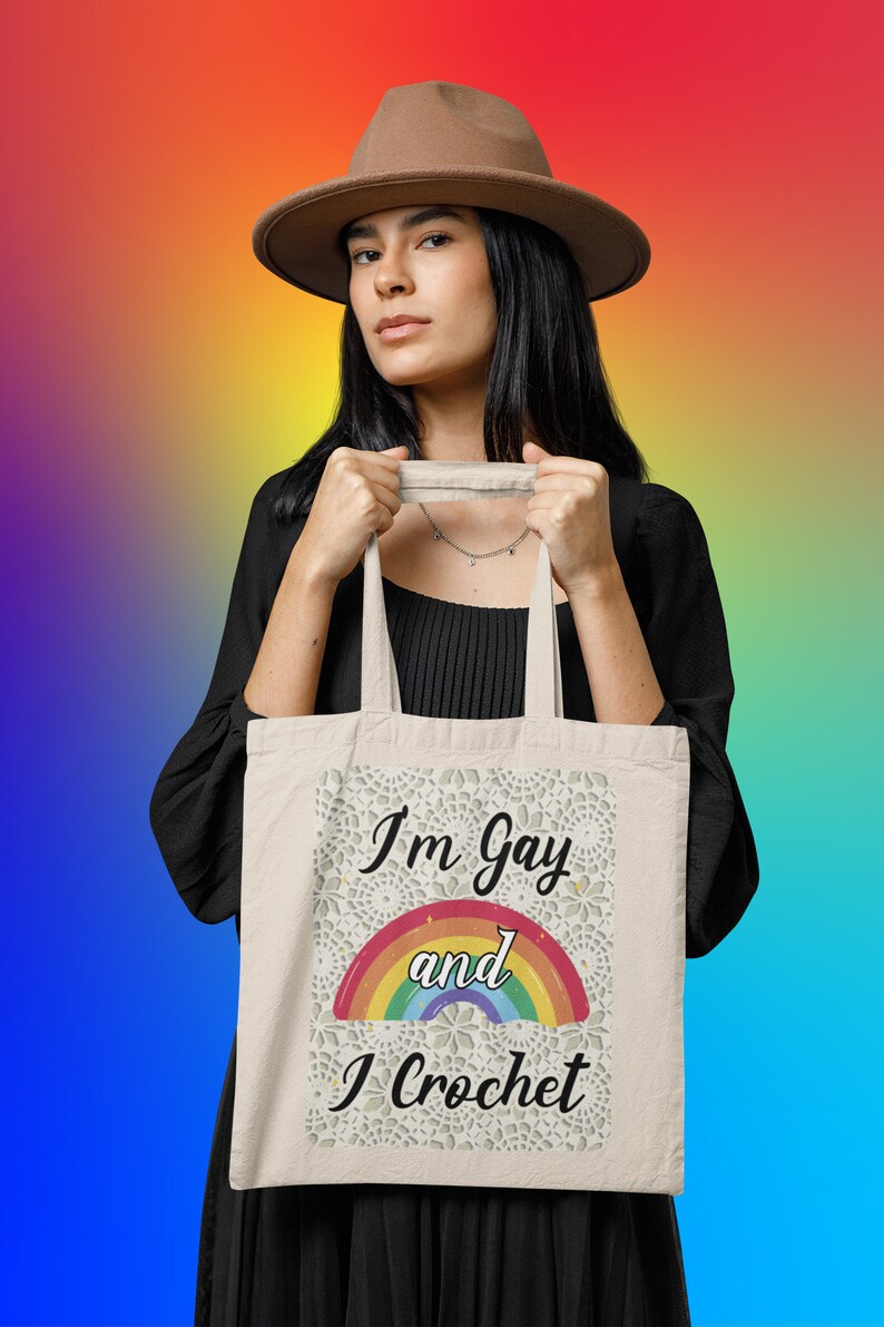 K&ouml;nnte beinhalten: Eine wei&szlig;e Einkaufstasche mit einem Regenbogen und dem Text "I'm Gay and I Crochet".