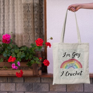 K&ouml;nnte beinhalten: Eine wei&szlig;e Einkaufstasche mit einem Regenbogen und dem Text "I'm Gay and I Crochet".