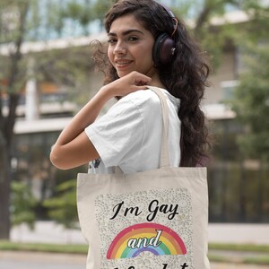 K&ouml;nnte beinhalten: Eine beige Tragetasche mit einem Regenbogen und dem Text "I'm Gay and I Crochet" darauf gedruckt.