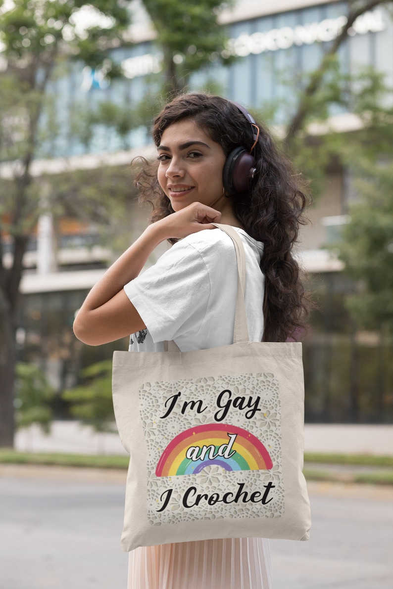 K&ouml;nnte beinhalten: Eine beige Tragetasche mit einem Regenbogen und dem Text "I'm Gay and I Crochet" darauf gedruckt.