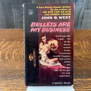 May include: A paperback book cover with a black background and white text. The title is "Bullets Are My Business" and the author is John B. West. The cover features a black and white illustration of a man holding a woman.