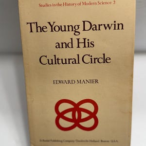 May include: A vintage book titled "The Young Darwin and His Cultural Circle" by Edward Manier. The cover is a light tan color with dark red text and a red intertwined symbol. The book is part of the "Studies in the History of Modern Science" series.