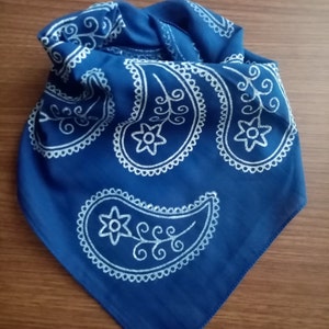 May include: A blue bandana with a white paisley pattern. The bandana is folded in a triangle shape.
