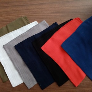 May include: A set of ten fabric squares in various colors, including green, white, gray, navy blue, black, and red. The squares are arranged in a staggered pattern, with the green square at the top and the red square at the bottom.