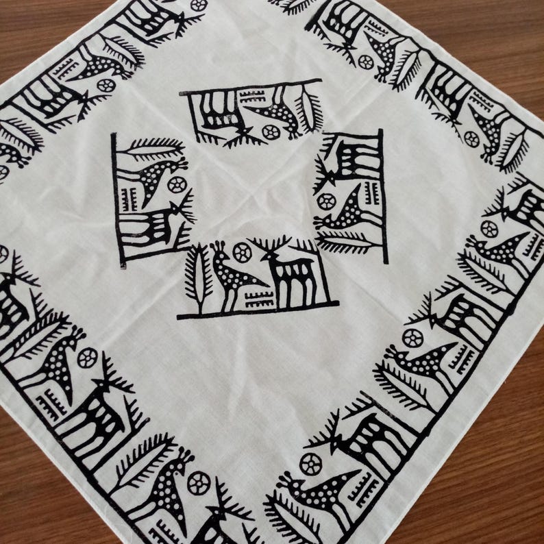 May include: White cotton fabric with a black and white print of stylized deer and geometric patterns. The fabric has a square shape and a border of the print.